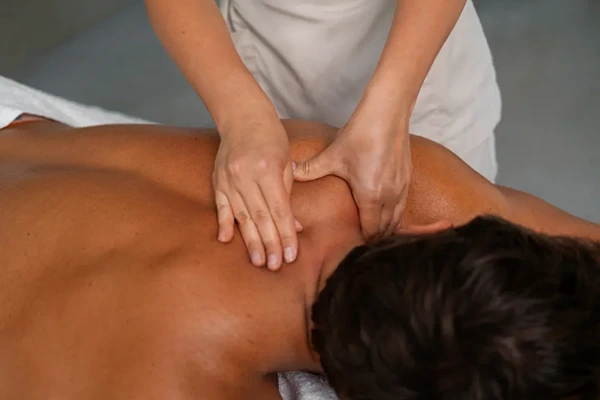 Trained male massage therapist helping a client improve physical wellbeing and flexibility with full body therapy.