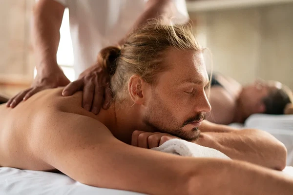 Male therapist setting up clean linens for authentic Thai massage session in hotel room across Delhi NCR