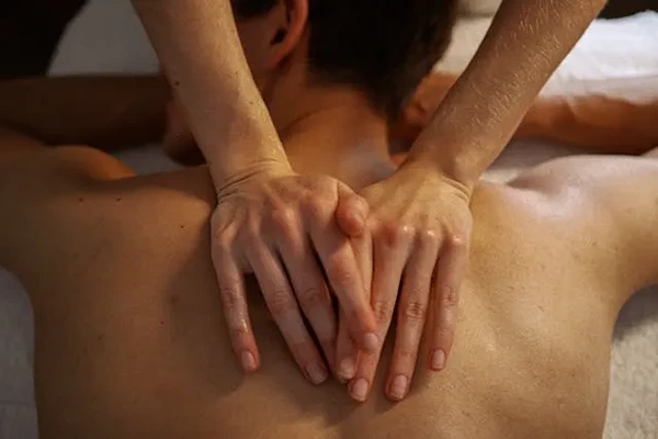 Male therapist providing a professional Swedish massage to a client in a comfortable home or hotel setting in Delhi NCR.